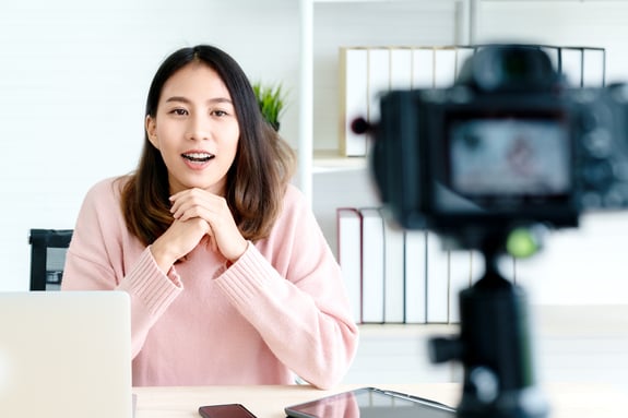 young asian american girl at desk sitting in front of camera