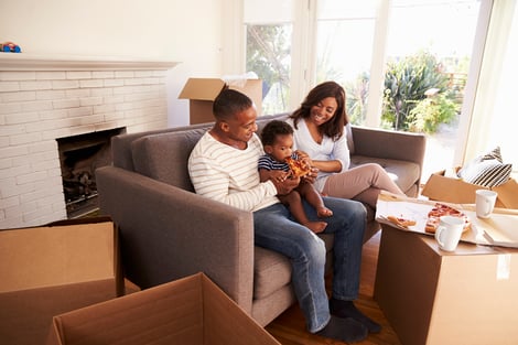 young urban couple feeding baby pizza in new house